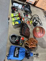 Top view of the lot showing basketball, baseball gloves, tennis balls, bike locks, hammock, pump, and other equipment arranged on a table.