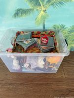 Photo of plastic storage tote filled with various mystery items including plush toy and stacked CDs inside fabric basket.