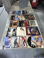 Top-down photo showing a spread of vinyl record albums arranged on a table in multiple rows showcasing various album covers.