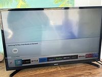 Samsung 32 inch smart TV powered on showing streaming app interface.