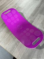 Top view of purple curved plastic Simply Fit exercise balance board with two handles and grip dots.