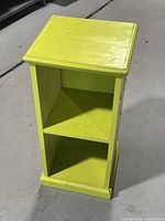 Front view of the small green wooden shelf showing two open shelves.