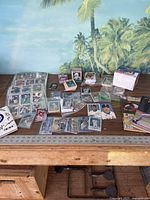 Collection of various sports cards laid out on table, some in protective sleeves and some loose, accompanied by a box and collector book.