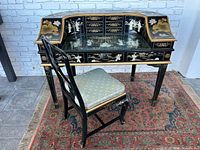 Full view of desk and chair showing black lacquer finish, mother-of-pearl inlays, glass inset, and curved side galleries