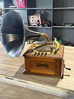 Side view of The Grafonola by Guild, a vintage-style record player with a large horn speaker and wooden base, showing the details and condition.
