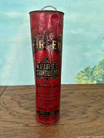 Front view of vintage fire extinguisher showing brand shield and instruction text, red metal body with signs of wear and aging.