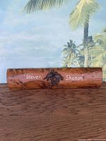 Full view of rectangular wooden coat hanger with lacquer finish, showing painted names and central metal bird hook.