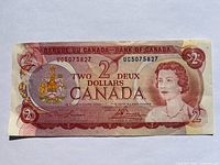 Front view of the 1974 Canadian 2 dollar paper currency note showing portrait and coat of arms.