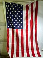 Front photo showing entire American flag with thirteen horizontal red and white stripes and a blue field with fifty white stars.