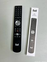 Front view of Bell Fibe TV slim remote Model 761C alongside instruction sheet with button layout visible.