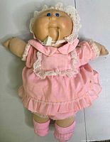 Front view of the vintage Cabbage Patch Doll wearing pink lace dress, showing overall condition and wear.