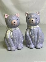Front view of the two hand-painted purple ceramic cat salt and pepper shakers showing details and scarves.