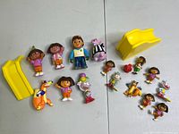 All Dora the Explorer figures and accessories from the lot, arranged on a white surface. Shows scale and quantity.