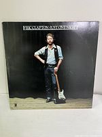 Front cover of Eric Clapton - Just One Night double vinyl album showing the artist with guitar against black background.