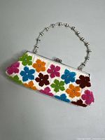 Front side of the purse showing colorful flower designs and beaded handle
