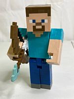 Front view of Minecraft Steve figure holding bow and arrow, showing pixelated block-style design and color details.