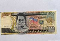 Obverse side of 2004 Philippine 500 Peso banknote showing portrait, serial number, flag, anti-counterfeit features and denomination markings.
