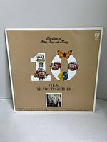 Front cover of the vinyl album titled The Best of Peter, Paul and Mary - Ten Years Together featuring beige background with decorated '10'.