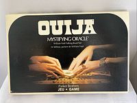 Top view of the original box showing the Ouija board with hands and planchette image, titled 'OUIJA Mystifying Oracle' by Parker Brothers in English and French.