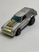 Front angle of the vintage 1975 Hot Wheels Poison Pinto with chrome finish, blue-tinted windshield, exposed engine, and visible wear.