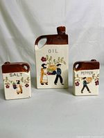 Front view of the 3-piece ceramic set including oil bottle, salt and pepper shakers with hand painted design and crackling glaze.