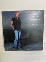 Front cover photo of the Willie Nelson album 'Somewhere Over The Rainbow' showing artist standing with a dark cloudy backdrop.