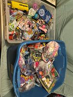 Two plastic bins filled with assorted vintage McDonald's Happy Meal toys including various plastic figures and packaged items, plus some unrelated toys.