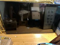 Front view of the unpowered Sony 65" TV laid upright on floor showing screen and bezel