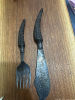 Photo showing antique fish server fork and knife with textured handles and engraved blade