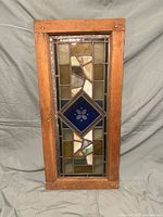 Front view showing full stained glass window door with blue diamond centerpiece and wooden frame