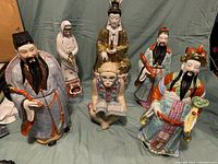 Full group of six Chinese porcelain statues arranged on fabric backdrop
