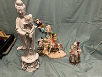 Wide shot of all three Chinese porcelain statues against a green backdrop showing the relative size and condition.