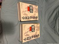 Two hardcover books stacked, showing covers with Chinese titles and traditional seal art.