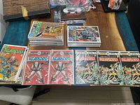 Photo showing stacks of multiple DC Comics The Warlord comic books on table, bagged and boarded. Several duplicates of issue 1 visible.