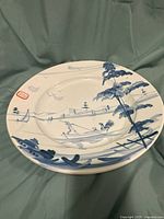 Front view of the large deep plate with hand-painted blue scenic river/boat scene