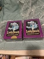 Two boxed Lady Death and the Women of Chaos chocolate bars side by side, both in purple packaging with character artwork.