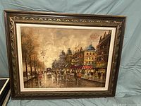 Frontal view of the oil painting, showing the entire city street scene on canvas with ornate frame.