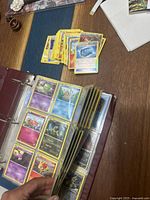 Three-ring binder open on table with loose cards stacked beside it