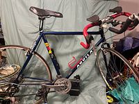 Full left-side view of blue Aquila road bike with red handlebar tape and aero extensions