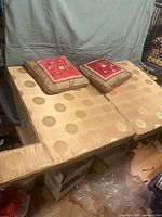 Four gold silk cushions displayed on a flat surface. Two cushions have removable red covers with Asian embroidery and two cushions show the gold silk fabric with circular motifs.