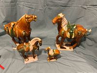 Full set of four Tang Dynasty style war horse porcelain figurines with brown sancai glaze, showing size and detail.