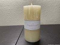 Front and top view showing the ivory flameless wax candle with label, battery-operated LED light on top, and price tag.
