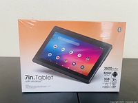 Front of sealed tablet box showing 7 inch screen with Android interface, icons, and tablet specifications like 3500mAh battery, 32GB ROM, 3GB RAM