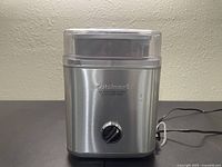 Front view of the silver Cuisinart ice cream maker machine, showing the control dial and power cord.