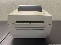 Front view of Zebra LP2844PSAT printer showing label output slot, slightly yellowed off-white casing and blue power button.