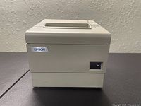 Side view of Epson TM-T88IV receipt printer showing power switch and Epson logo on the front face, beige casing.
