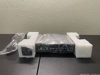 Cisco SG300-10PP switch wrapped in plastic with white foam corner protectors, front view showing Ethernet ports.