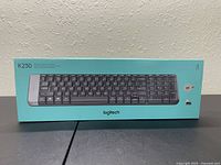 Front view of Logitech K230 wireless keyboard packaging in turquoise box with product image and model number.