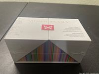 White rectangular sealed box of Steam Originals Steam Kubes with faint floral embossing, butterfly logo, and visible colorful stripes inside.