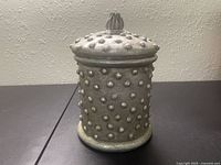 Front view of vintage silver grey canister with raised dot texture and lid with decorative knob.